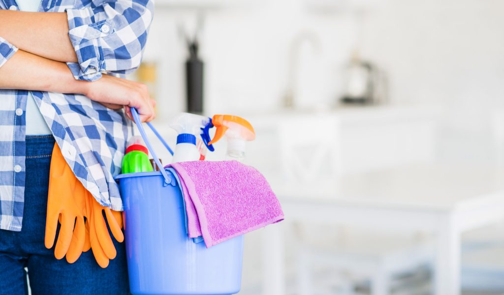 close-up-of-woman-s-hand-holding-bucket-with-cleaning-supplies-and-pink-napkin